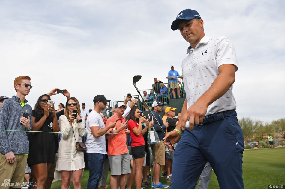 泳坛传奇迈克尔·菲尔普斯戴着墨镜，在赛场边专注地观看高尔夫球星们的表演