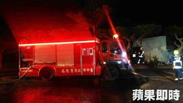 消防员架设水枪阵地，奋力阻击向仓库蔓延的熊熊烈焰，水柱与浓烟交织在一起。