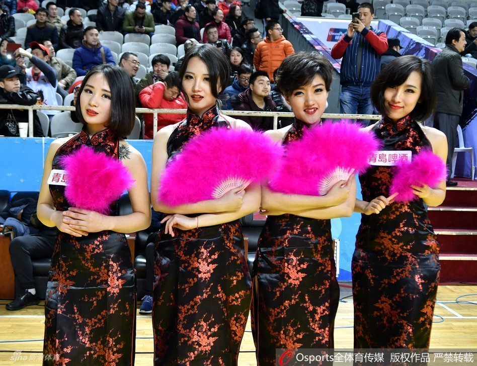 身姿曼妙的啦啦队员身着火红旗袍，高开衩设计下大长腿若隐若现，她在舞台上轻盈旋转，姿态优美得如同冬日里绽放的红梅，既古典又时尚。