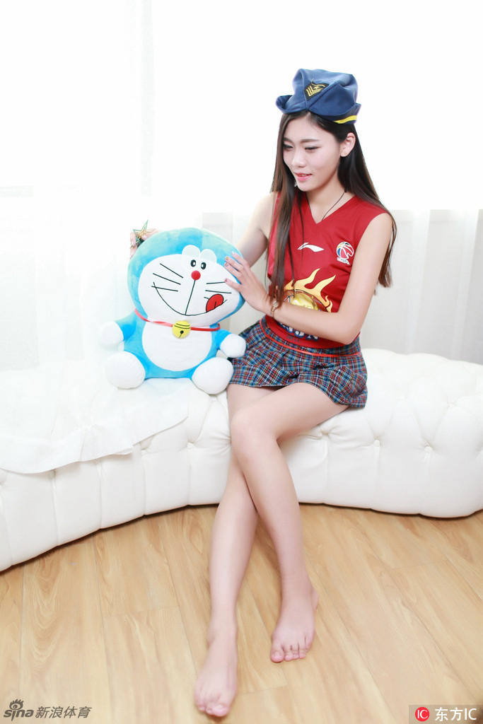 她双手高举玩偶挡在眼前，只露出一双会说话的眼睛，纤细的手臂和白皙的长腿在阳光下闪闪发光