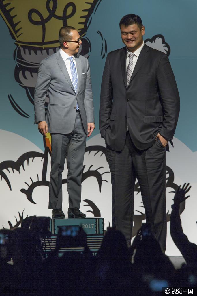 霍启刚与霍启山两兄弟并肩站在论坛背景板前，两人皆穿着正装气质儒雅，面对镜头露出谦逊而自信的笑容，展现出霍家第三代沉稳干练的风采。