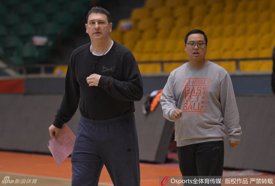 训练场上，一名队医正蹲在地上，神情专注地为坐在凳子上的球员进行腿部包扎，旁边的队友们投来关切的目光。