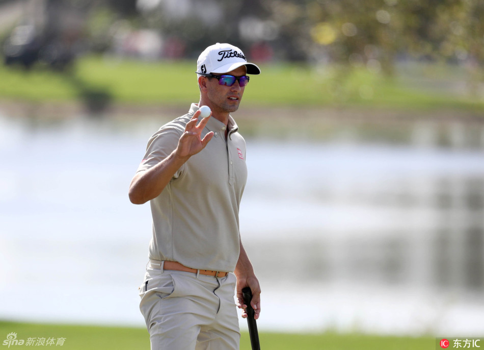 亚当·斯科特在果岭边向观众挥手致意，标志性的挥杆姿势与谦和笑容尽显卫冕冠军风范。
