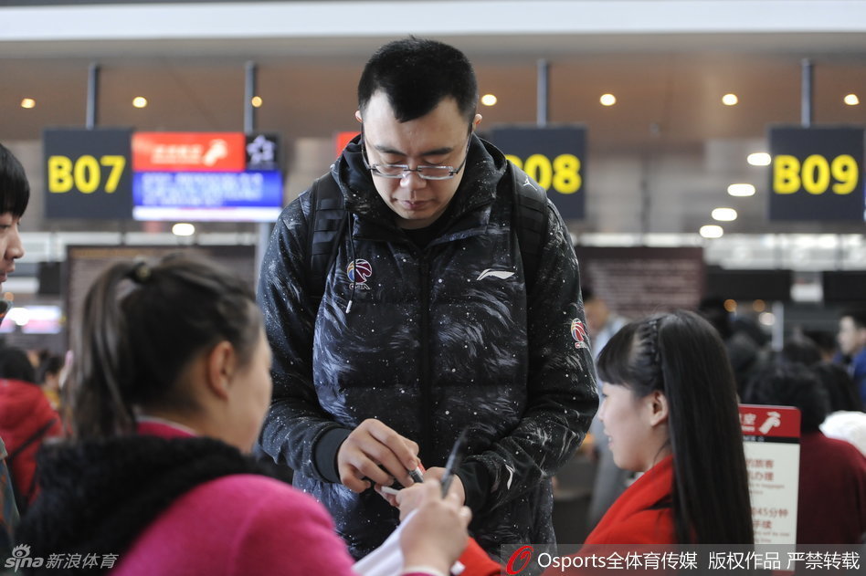 韩德君弯下巨大的身躯，将耳朵凑近一位坐着轮椅的老奶奶，耐心听她说话，手中的笔一直悬停在照片上等待签名