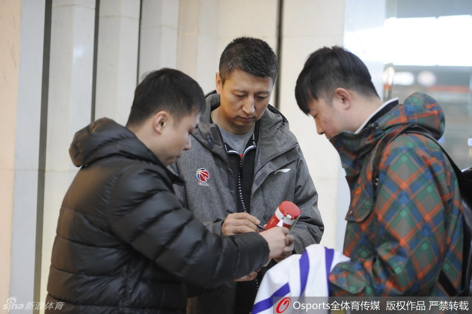 主教练郭士强被几位老球迷围住，他双手递回签好名的战术本，眼角的笑纹透露出对这份支持的感动