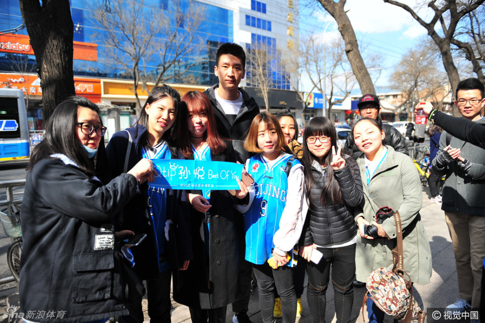 孙悦和方硕在品牌店内与热情的球迷们近距离互动，两人神情专注，正低头为球迷手中的纪念品签下名字，现场气氛高涨