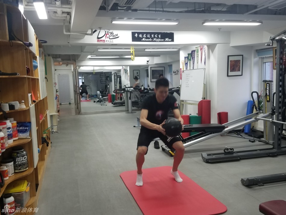 孙悦在康复师的辅助下进行平衡训练，单脚站立时表情专注而吃力，核心收紧，汗水已经浸湿了他的训练背心。