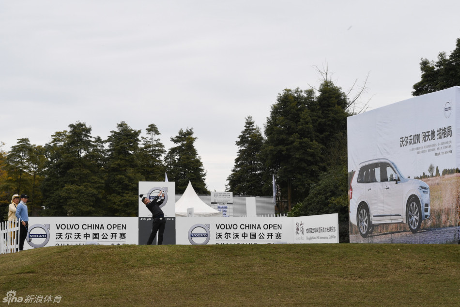 冠军叶剑峰在颁奖仪式上高举奖杯，笑容灿烂，背后是美丽的球场夕阳