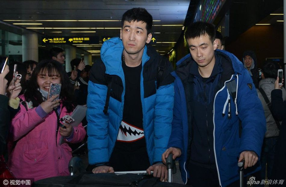 刘志轩身穿深色休闲服,神情虽显旅途劳顿后的倦意,但嘴角上扬露出温和的笑容,正与一位男球迷并肩站立合影,眼神中透着谦和。