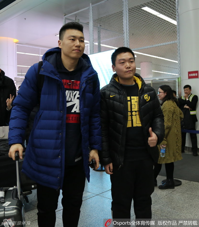 李根被热情的球迷层层包围，他手拿签名笔，正低头为一位身穿他球衣的小球迷签名，脸上挂着亲切的笑容。