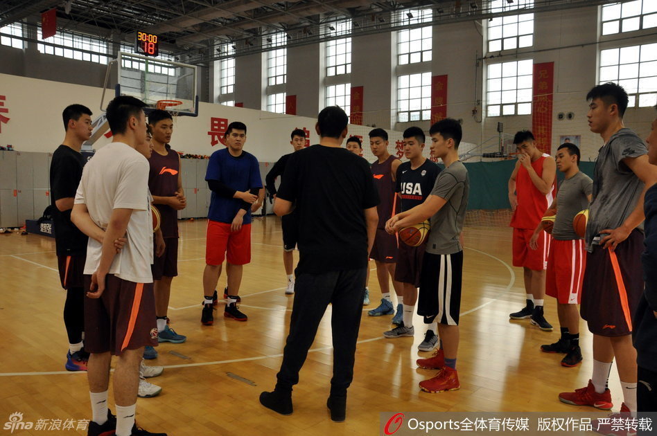 训练馆内,主教练李楠正在给全队训话,他表情严肃地挥手强调战术纪律,队员们围绕在身边,汗水湿透了球衣,神情专注。