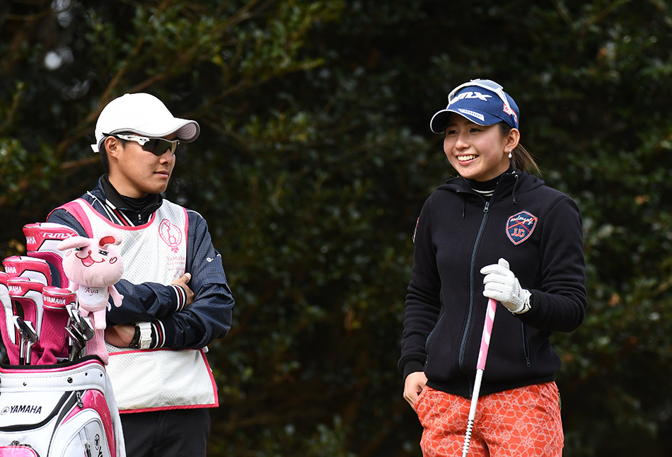 尹寀瑛在推杆果岭上弯腰仔细观察线路,她的倒影与绿茵融为一体,展现高尔夫运动的静谧与专注。