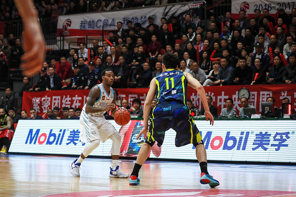 新疆队外援布拉切篮下卡位后高举双臂忘情庆祝,身后是周琦与广东队员易建联、周鹏的激烈拼抢背景