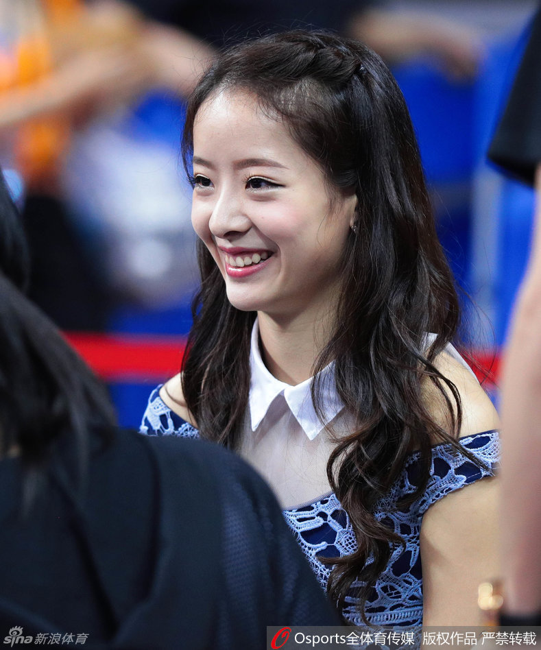 周鹏妻子刘美身穿鲜艳红衣在场边为广东队助威，神情专注，温婉大气中透露出对丈夫的坚定支持