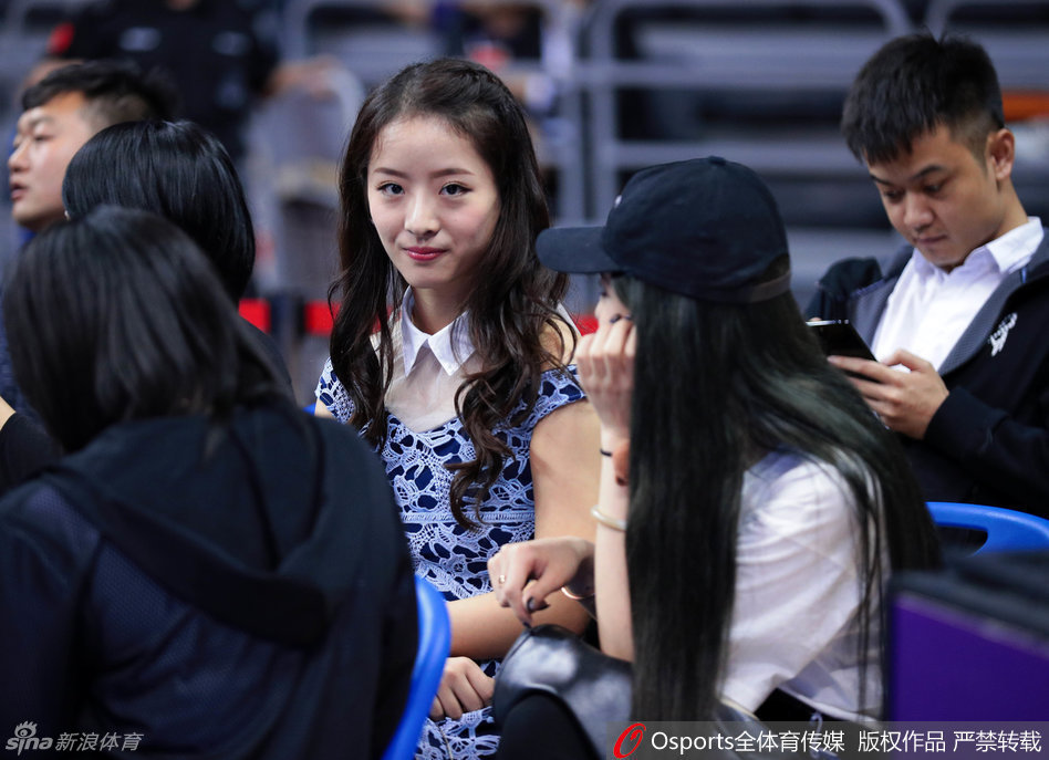 周鹏妻子刘美在看台上专注观赛，身穿红衣的她表情恬静，默默为场上的丈夫加油鼓劲