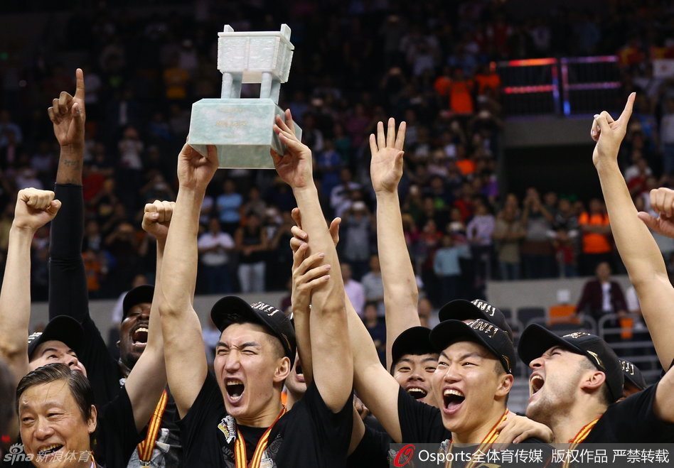 新疆队的全体将士身穿冠军T恤，共同托举起那尊象征着最高荣誉的CBA总冠军奖杯，大家紧紧靠在一起，笑容定格在这一历史瞬间，画面充满了团结与喜悦。
