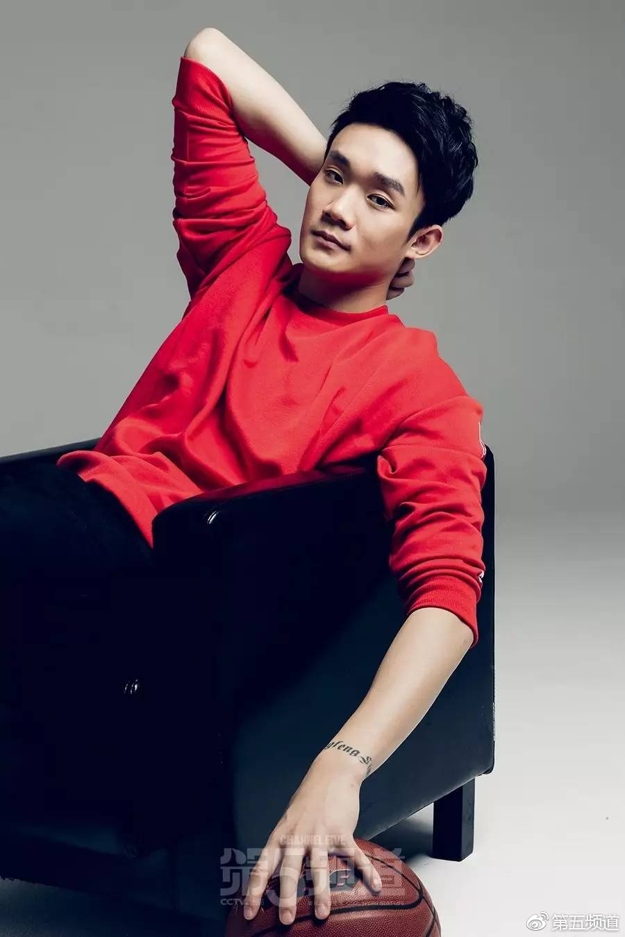 丁彦雨航单手托腮陷入沉思，格子衬衫搭配休闲裤的造型显得书卷气十足，仿佛在思考着篮球哲学或是对未来的无限憧憬。