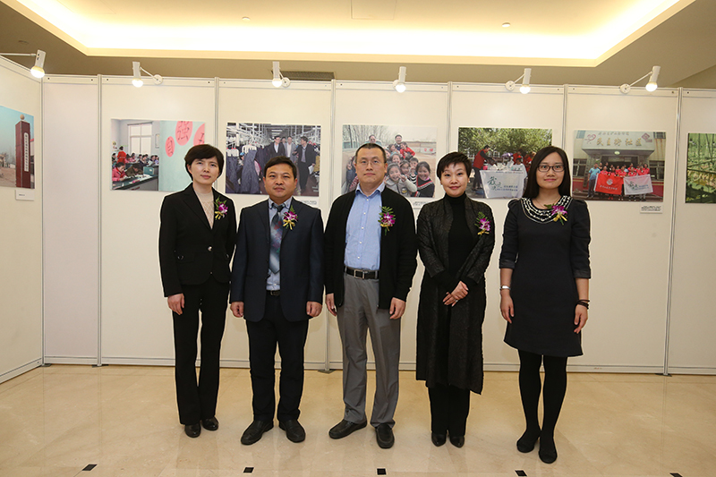 金融企业扶贫成就摄影展剪彩仪式。图为剪彩嘉宾在金融企业扶贫摄影作品前合影留念。