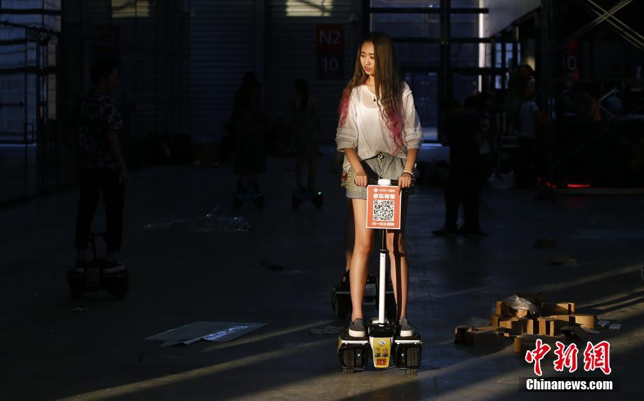 图为29日彩排时，有几个showgirl被安排坐平衡车向观众招手，也引起了槟语的好奇，她也想来试试。中新社发 张浩 摄