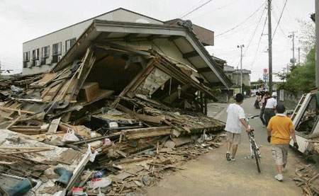 图文:行人从新潟县受地震毁坏房屋旁走过