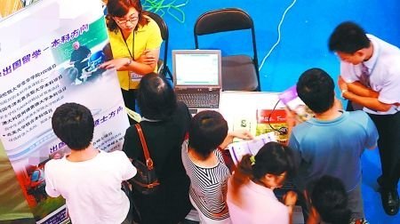 在一国际教育博览会上,学生和家长围在展台前咨询留学情况。 (资料图片) 在一国际教育博览会上,学生和家长围在展台前咨询留学情况。 (资料图片)