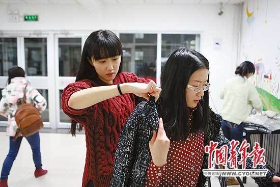 12月18日,中国人民大学,一位校友在试穿康逸琨(左)销售的外套。中国青年报记者 赵迪摄 12月18日,中国人民大学,一位校友在试穿康逸琨(左)销售的外套。中国青年报记者 赵迪摄