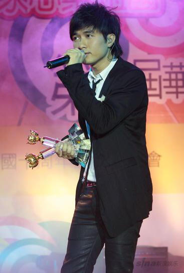 图文:古巨基手捧奖杯 雨中深情演唱获奖歌曲
