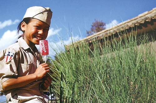 昆明空军基地附近稻田里，队员仿制了一套美军军装送给一个小女孩，为她拍下了这张拿着棒棒糖的照片。（艾伦·拉森摄）