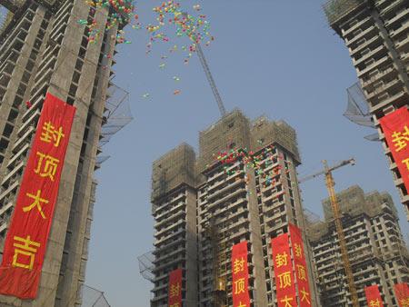 条幅悬挂在楼体上,一朵朵彩色旗帜伫立在楼顶端随风摆动……整个工地