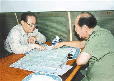 1998年8月13日,江泽民同志在飞往长江抗洪一线的飞机上听取张万年同志汇报抗洪兵力部署情况。