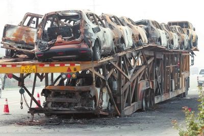 一辆加长大货车“瘫”在路上，后面的轮胎均被烧化，两层车厢里，18辆皮卡车都烧得只剩下铁架子　　□记者李岚文 闫化庄摄影