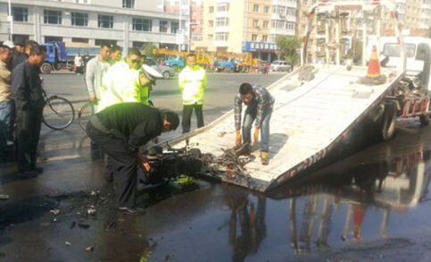 现场人员正在将烧成遗骸的摩托车拖走