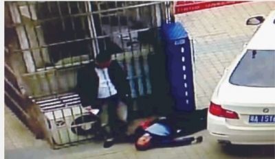 男子右手拿着一叠钞票站在被打倒的保安身边。(视频截图) 男子右手拿着一叠钞票站在被打倒的保安身边。(视频截图)