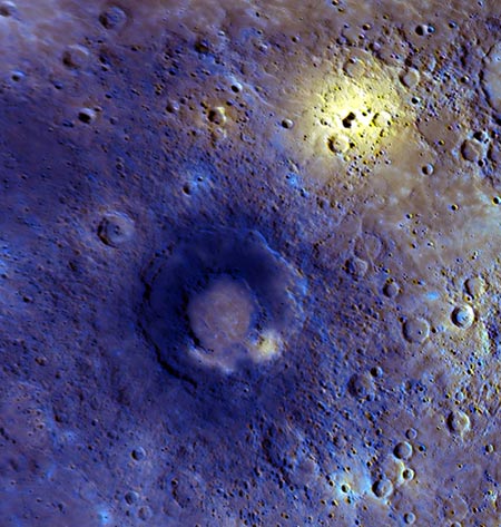 这张全彩图（enhanced-color）显示的是水星表面的一个区域，“信使”号在第三次飞越时，获得这个地区的详细信息。从图上可知，这里的火山活动显然非常剧烈。右上方附近的嫩黄色区域，是一个无边的低压区中心，这里可能是爆发的火山口所在地。图片中心的双环盆地的内部平坦，这可能是火山作用产生的结果。