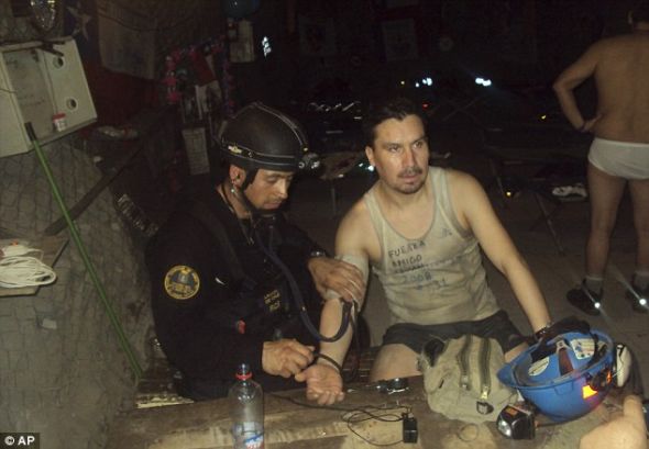 一名智利海军人员正为被困矿工爱迪生·佩纳（右侧）检查身体，此时的他正等待营救，离开被困两个多月的圣何塞铜矿。