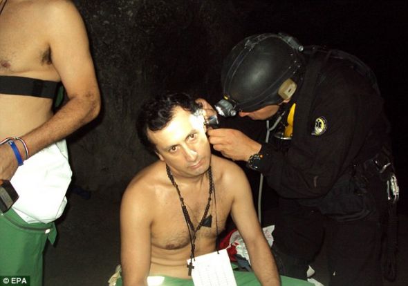 在等待升井过程中，被困矿工保罗·巴斯托斯接受一名医疗人员的健康状况评估