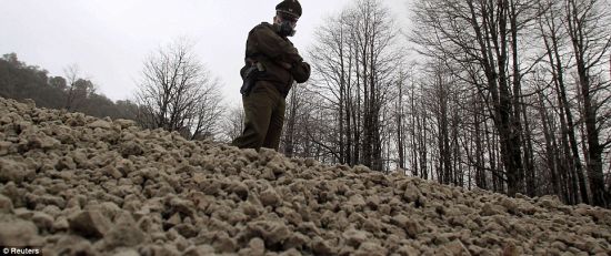 佩戴面罩防止毒气入侵的警员站在火山喷发产生的大量浮石上