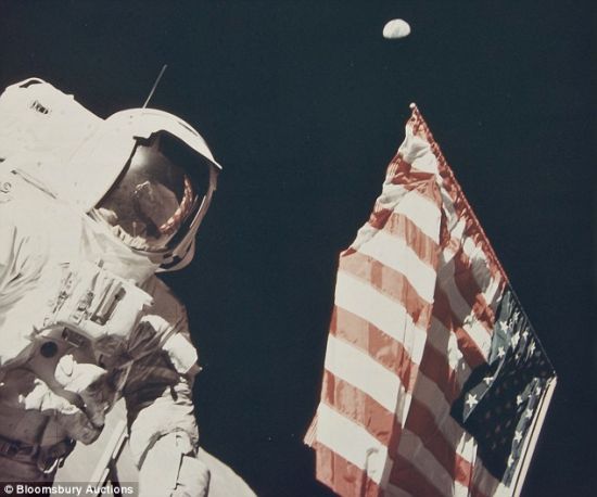 　　哈里森-施密特与美国国旗，高悬于夜空中的就是人类家园地球。这幅照片最后拍出1100英镑(约合1759美元)
