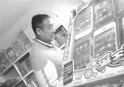  一名店主向记者展示祭祀用的“苹果手机”  摄/特稿记者  秦胜利