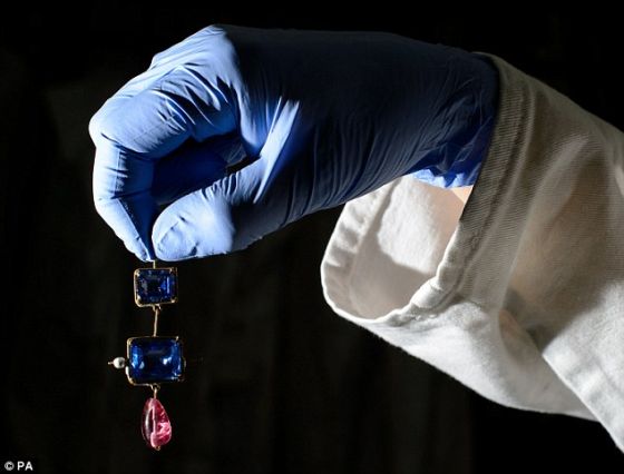 　　伦敦博物馆的一名管理者拿着一个黄金珐琅垂饰，上面镶嵌着两块蓝宝石。这件首饰同样是齐普赛宝藏的一部分