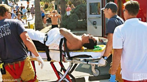 救生员和医护人员将被咬伤的泳客送上救护车。