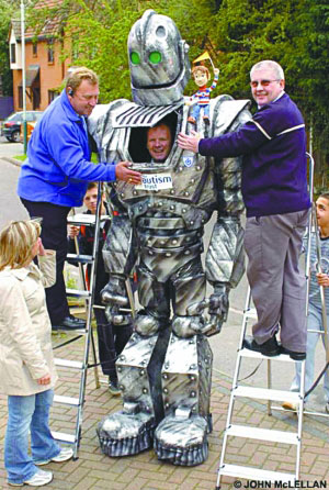 劳埃德·斯科特在人们的帮助下穿上机器人服装。