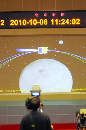 一名电视摄像人员在拍摄指控大厅显示屏上显示的嫦娥二号卫星第一次近月制动模拟动画。新华社记者 田兆运摄 