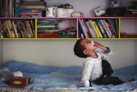 ②出租屋内，图图坐在床上自己吃药。 组图/潇湘晨报记者陈正 