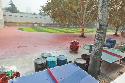 纬三路小学尚未施工结束的塑胶跑道，操场旁放着许多桶。