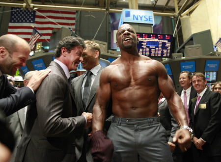 图为该片的主演之一克鲁斯(Terry Crews)在交易大厅内脱衣秀肌肉，他身边的著名动作片巨星还有斯坦森(Jason Statham，左1)、史泰龙(左2)和龙格尔(Dolph Lundgren)