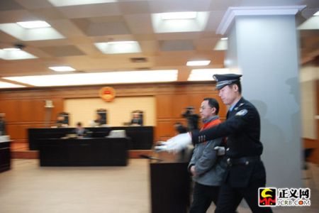 炮制国内“操纵证券市场第一案”的股市“黑嘴”汪建中，今天上午在北京市第二中级人民法院受审。图为汪建中被法警带入法庭。