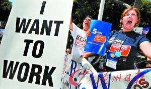 　8月13日，在美国洛杉矶，几名抗议者在写有“我要工作”的标语后参加集会，要求工作机会。