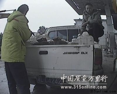 中石油员工在往23个塑料大桶内加油。