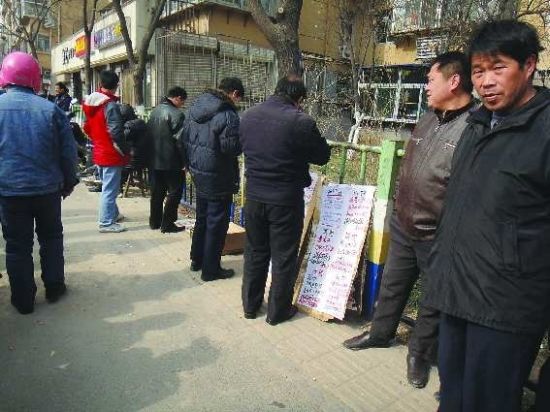9日上午，在经八路劳务市场，几名农民工正在看路旁的招聘信息。 见习记者 林媛媛 摄